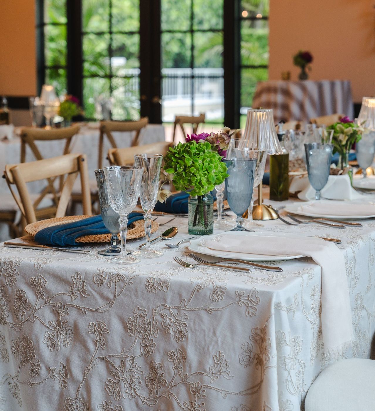 Long tables dressed to the floor in Marcella taupe, an ivory linen with cream cord embroidery of blossoms on vines