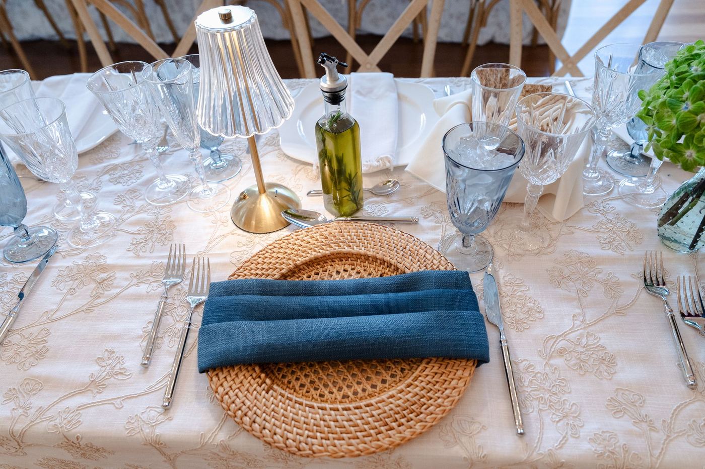 Honey Rattan charger on the Marcella tablecloth with a folded midnight blue napkin and silver flatware