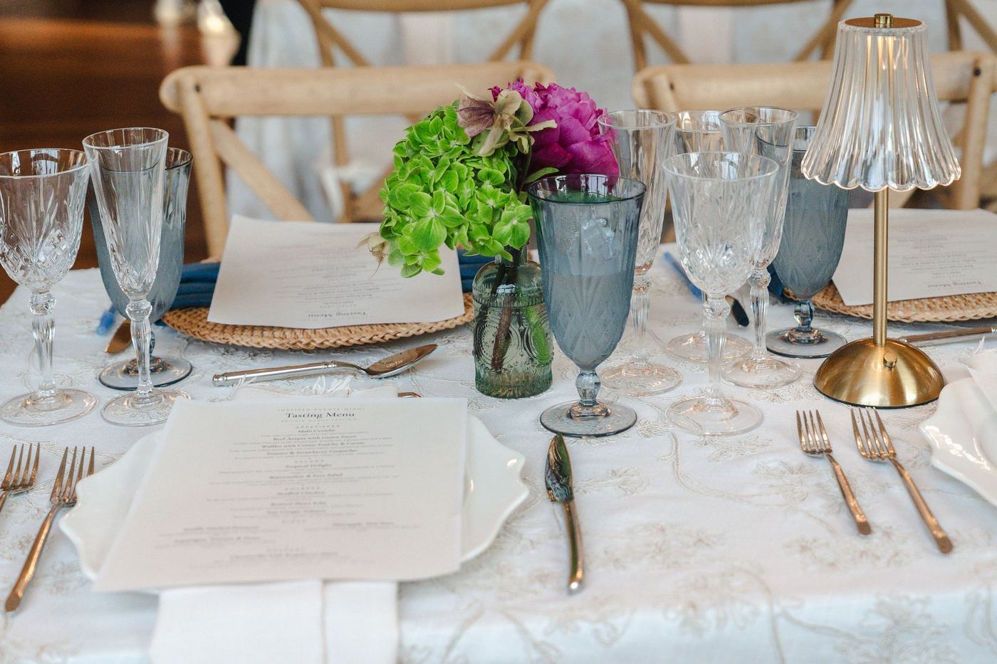 Crystal Cut wine glasses and flutes beside blue Crystal Cut water glasses, menus and a cordless lamp