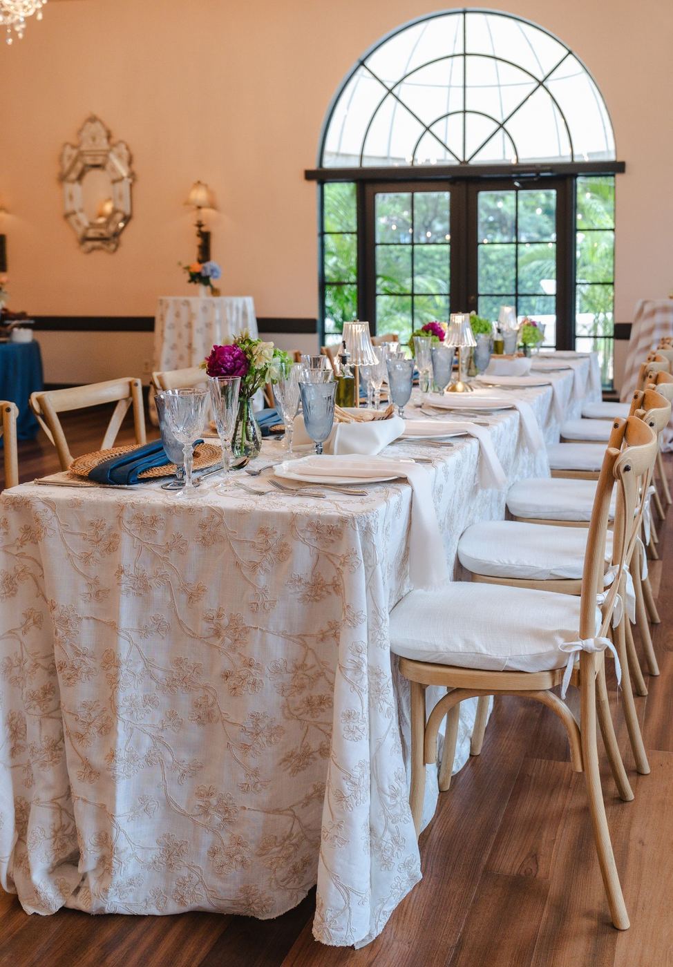 Crossback chairs pulled up to a long table under an arched window at Coral Gables Country Club